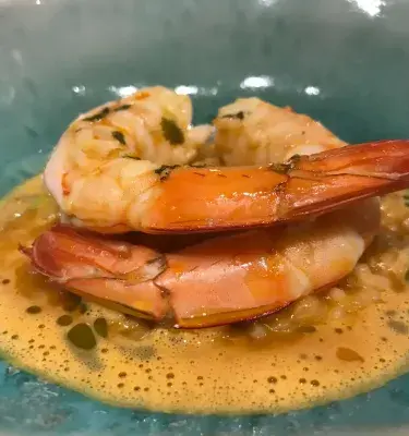Plato de camarones en salsa servido en un plato azul
