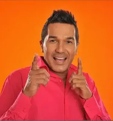 Hombre sonriente con camisa fucsia posando frente a fondo naranja