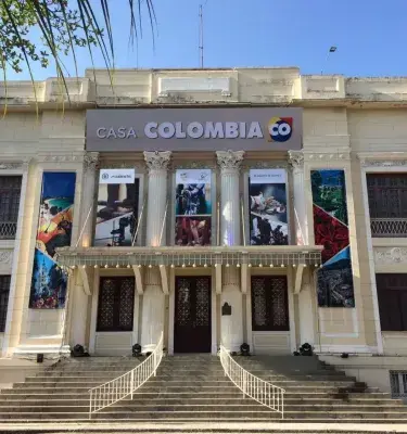 Fachada de un edificio colonial con la inscripción "CASA COLOMBIA CO" y banderas de Colombia a los lados.