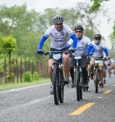 Ciclistas en uniforme blanco y azul pedaleando en carretera abierta.