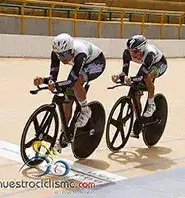 Dos ciclistas profesionales en bicicletas de pista con ruedas negras y uniformes de competencia.