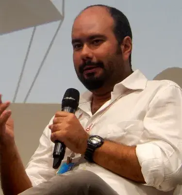 Man in white shirt speaking into microphone at an event or conference