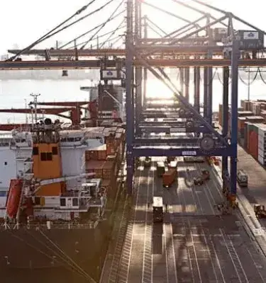 Puerto de contenedores en Colombia con grúas y barcos de carga al atardecer