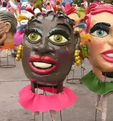 Masks of women's heads in a carnival parade or troupe.