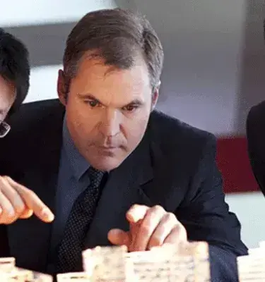 Tres ejecutivos, dos asiáticos y uno caucásico, analizan concentrados una maqueta arquitectónica.