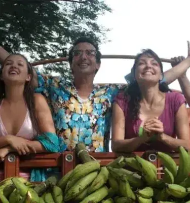 Happy family riding in a truck full of bananas, smiling.