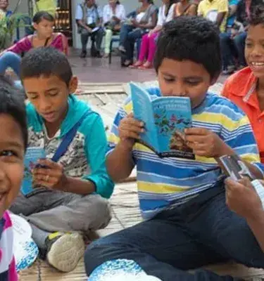 Niños sonrientes leyendo libros durante actividad cultural al aire libre