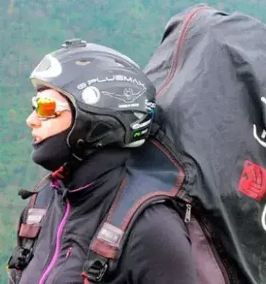 Mujer con casco y equipo de parapente lista para volar en zona montañosa