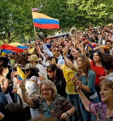 Crowd waving hands and Colombian flags at a festival.