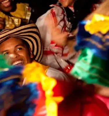 Bailarines de folclore con un hombre en un sombrero vueltiao sonriendo.
