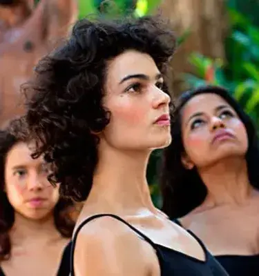 grupo de bailarinas y bailarines, con una mujer de cabello rizado en primer plano.