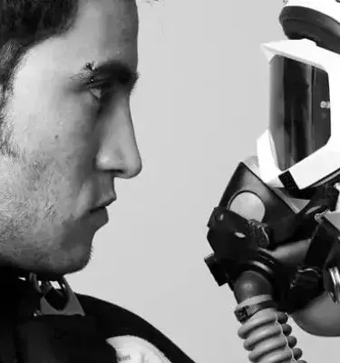 Joven sosteniendo un casco de piloto con visor y máscara de oxígeno