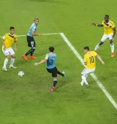 Jugador de Uruguay patea el balón frente a jugadores de Colombia.