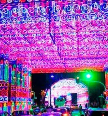 Túnel de luces navideñas magenta y azul sobre calle de ciudad.