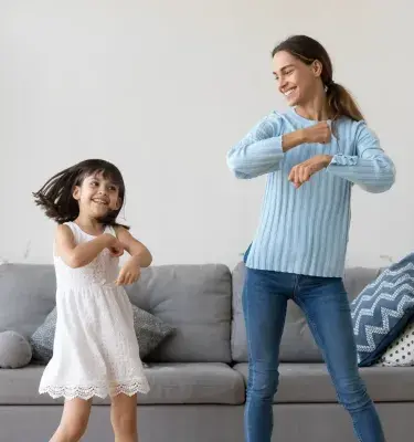 Madre e hija bailando en la sala de una casa