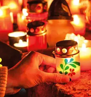 Mano encendiendo vela decorada en Día de las Velitas.