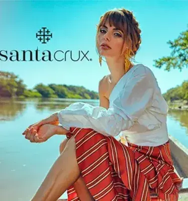 Woman in white blouse and striped skirt posing in boat on river with Santa Cruz logo