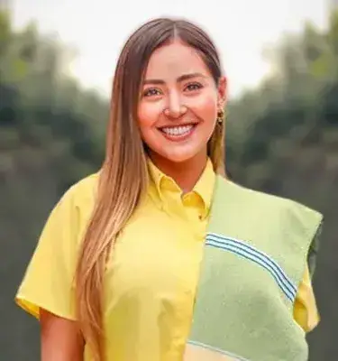 Mujer joven sonriendo con camisa amarilla y pañoleta tradicional