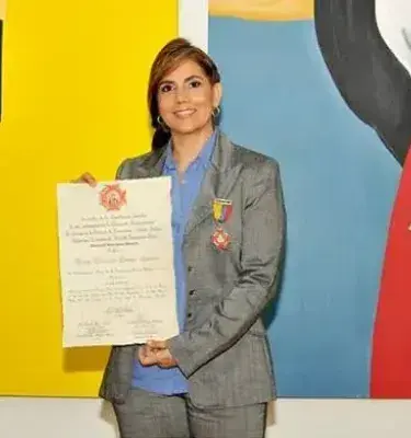 Mujer recibiendo reconocimiento con diploma y medalla frente a pinturas coloridas