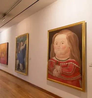 Botero Museum gallery with painting of woman in red dress.