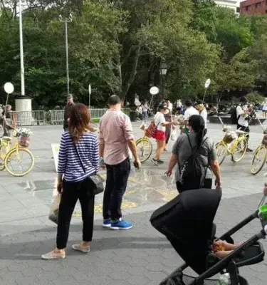 Personas en plaza interactuando con bicicletas amarillas de Colombia en paz