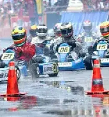 Pilotos compitiendo en karts bajo la lluvia