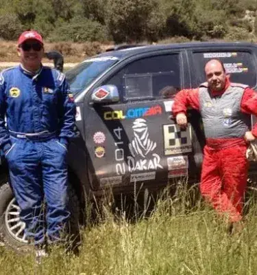 Dos pilotos de rally con su camioneta "Colombia" del Dakar en un camino.