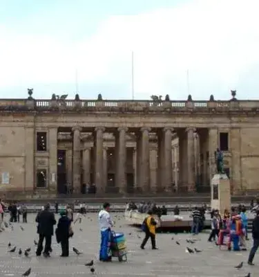 Personas caminando en la Plaza de Bolívar frente al Capitolio Nacional en Bogotá