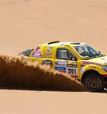 Camioneta amarilla de rally Dakar (número 391) conduciendo a alta velocidad y levantando arena.
