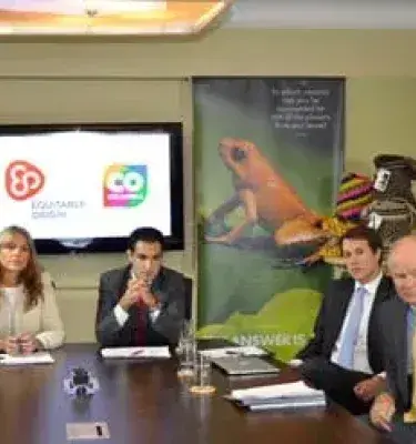 Business meeting with presentation and golden frog banner in the background.
