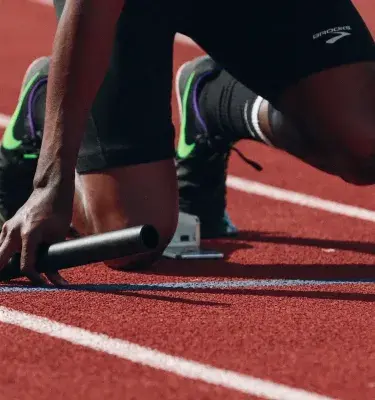Atleta en posición de salida para carrera en pista de atletismo.