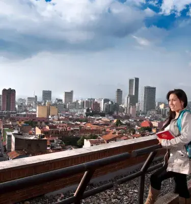 Estudiante con mochila observando el centro de Bogotá desde una terraza
