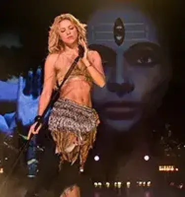 Shakira actuando en concierto con una imagen proyectada.