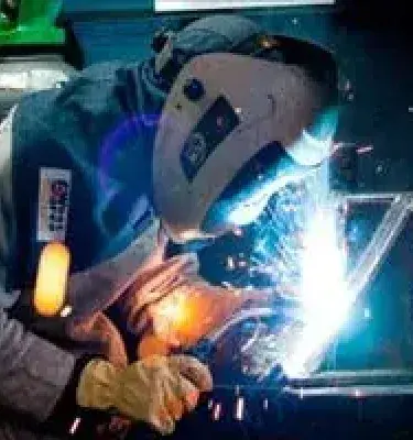 Soldador con equipo de protección trabajando con chispas en taller