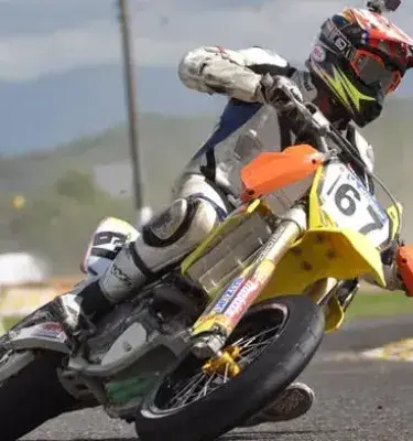 Piloto compitiendo en carrera de supermoto en pista asfaltada