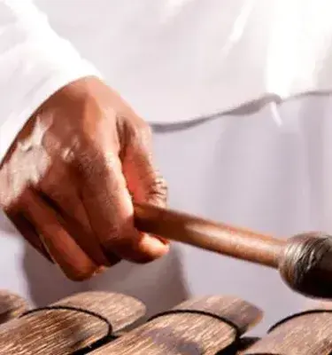 Hands playing a chonta marimba in a white costume.