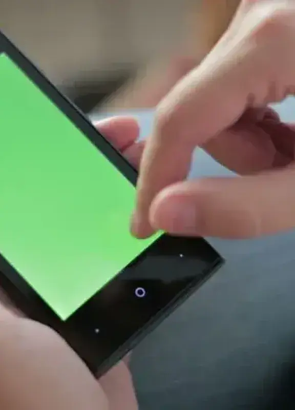 Persona usando un smartphone con pantalla verde sosteniéndolo con ambas manos