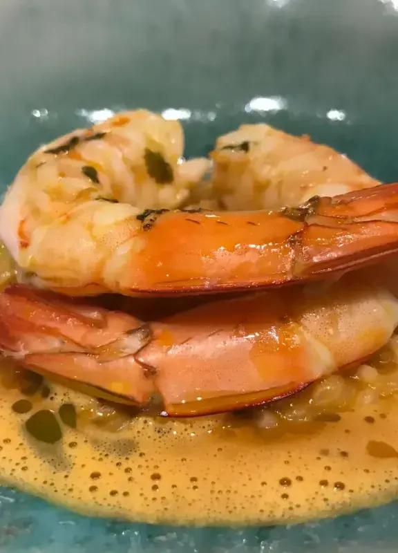 Plato de camarones en salsa servido en un plato azul