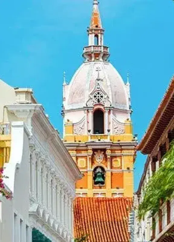 Calle colonial de Cartagena, Colombia, con balcones de madera y la cúpula de la Catedral al fondo.