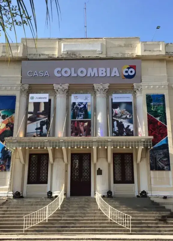 Fachada de un edificio colonial con la inscripción "CASA COLOMBIA CO" y banderas de Colombia a los lados.