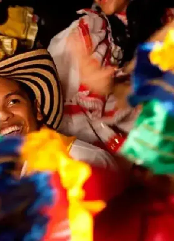 Bailarines de folclore con un hombre en un sombrero vueltiao sonriendo.