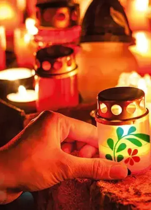 Mano encendiendo vela decorada en Día de las Velitas.