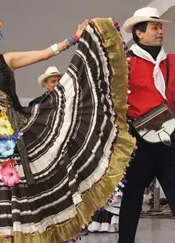 Couple dancing a folk dance in colorful traditional costumes.