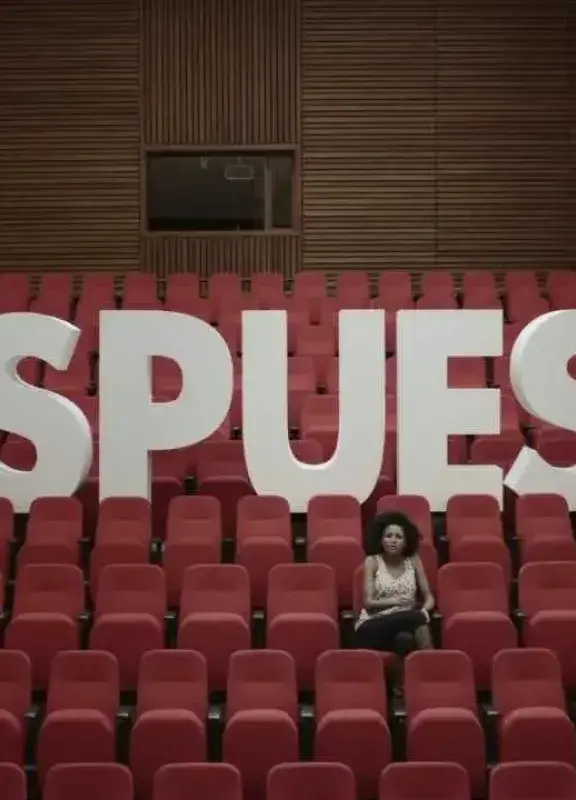 Mujer sentada frente a letras gigantes que forman la palabra RESPUESTA