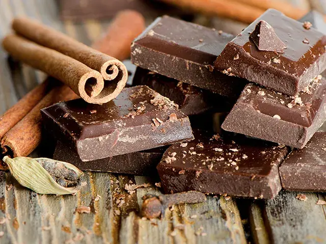 Chocolate negro con canela y cardamomo sobre madera.