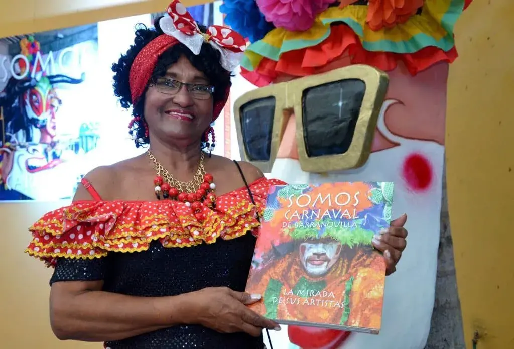Mujer disfrazada sosteniendo un libro del Carnaval de Barranquilla.
