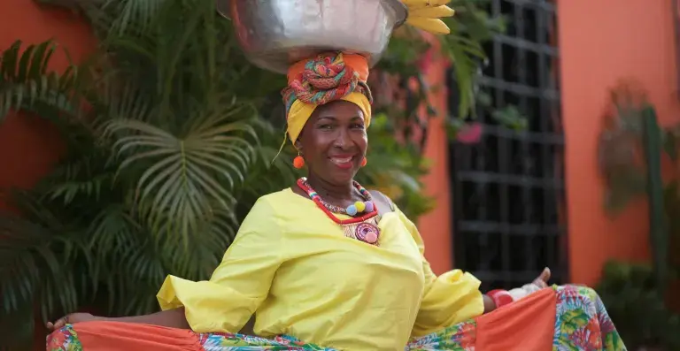 Afro-Colombian woman smiling with fruit on her head.