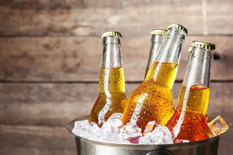 Botellas de cerveza fría en un balde con hielo sobre un fondo de madera rústica