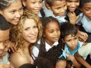 Shakira sonriendo rodeada de niños.