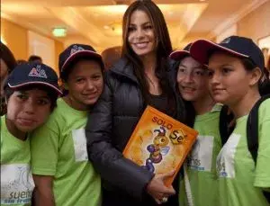 Sofía Vergara con niños sosteniendo un libro naranja.